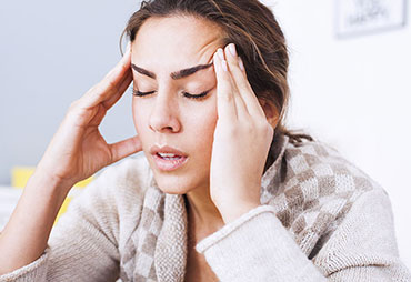 Woman sufferinf from headaches in need of acupuncture