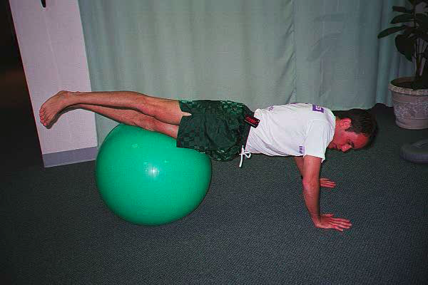 Dr. Ezgur performing Ball Walkout: Pelvic Rotation & Knee-to-Chest exersise